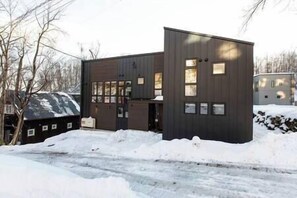 A modern two-story building with a dark exterior, large windows, and a flat roof.
