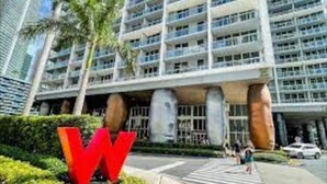 Un hôtel moderne, reconnaissable à son grand panneau en forme de « W », qui s’étend sur plusieurs étages et possède une vaste entrée surmontée d’un auvent.