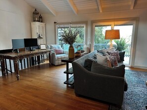 Een gezellige woonkamer met houten vloer, een bank, fauteuil, tafel en televisie.