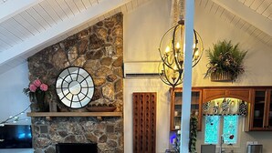 Un'ampia zona giorno con camino in pietra, un orologio grande e un'accogliente disposizione di posti a sedere.