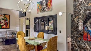 A modern dining area with a glass table, gold chairs, and a black-framed window. - Urban Loft Laureles : Modern, Elegant : A/C : Balcony (Medellín)