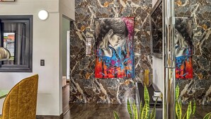 A modern interior with a marble wall, a large abstract painting, and a dining area with a golden chair. - Urban Loft Laureles : Modern, Elegant : A/C : Balcony (Medellín)