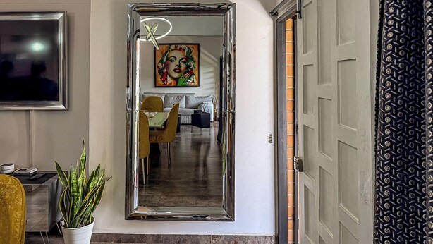 A modern interior with a dining area, a large mirror, and a potted plant. - Urban Loft Laureles : Modern, Elegant : A/C : Balcony (Medellín)