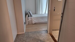 Une chambre à coucher avec un lit, une fenêtre avec des rideaux et une porte.