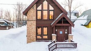 A two-story house with a steeply pitched roof, large windows, and a front porch with a railing. - Gouka Chalet by Elite Havens (Kutchan)