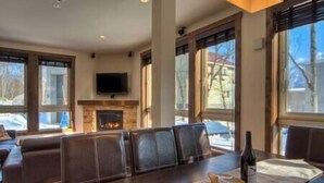 A spacious living room with a fireplace, large windows, and a flat-screen TV mounted above it. - Gouka Chalet by Elite Havens (Kutchan)