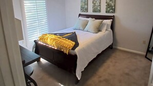 Une chambre à coucher avec un lit, un bureau et une fenêtre équipée de stores.