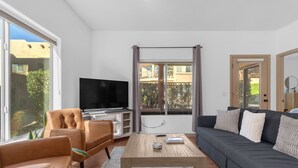 A modern living room with a sofa, armchairs, a coffee table, and a TV. - Cozy Condo in Beautiful Fountain Hills (Fountain Hills)