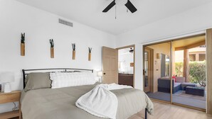 A bedroom with a bed, bedside table, and a view of an outdoor seating area. - Cozy Condo in Beautiful Fountain Hills (Fountain Hills)