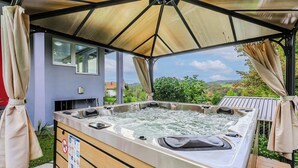 Ett bubbelbad under en överbyggd uteplats med utsikt över landskapet.