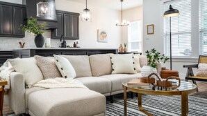 En moderne stue med en hjørnesofa, et sofabord og et spiseområde.
