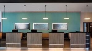 Zona de recepción con pared color turquesa, tres obras de arte enmarcadas y un mostrador con acabado en madera clara.