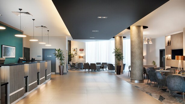 Un moderno vestíbulo de hotel con mostrador de recepción, zona de estar y un pilar grande.