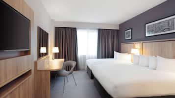 Una habitación de hotel con una cama grande, un escritorio con una silla, un televisor de pantalla plana y una ventana con cortinas.