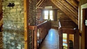 A wooden interior with a stone wall, wooden beams, and a wooden staircase. - Chalet-Style Log Home  – Waynesville, Ohio (Waynesville)