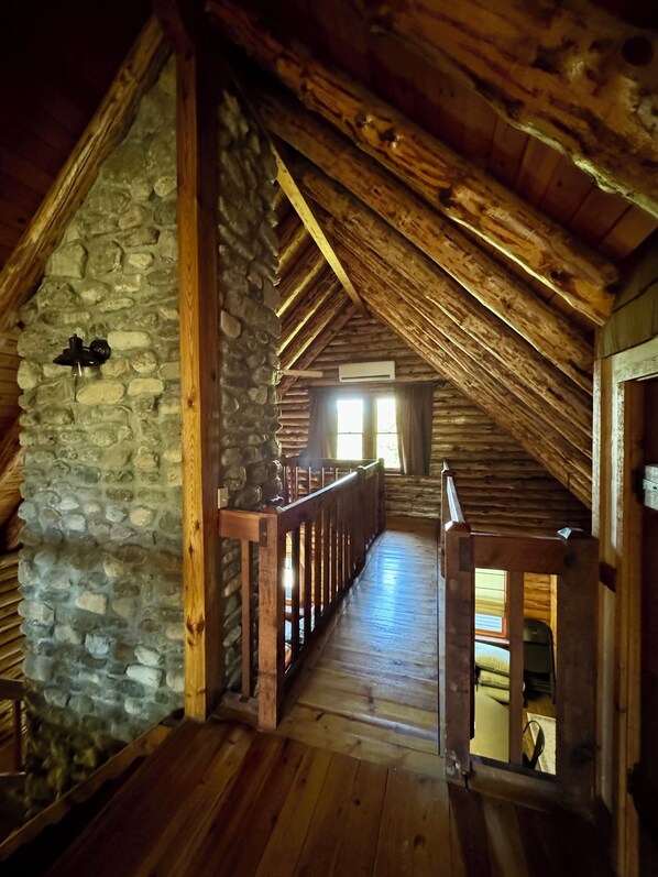 A wooden interior with a stone wall, wooden beams, and a wooden staircase.