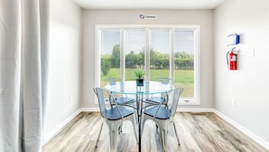 Une pièce moderne avec une table et des chaises en verre, de grandes fenêtres équipées de stores, un extincteur et le logo de Cessna sur le mur.