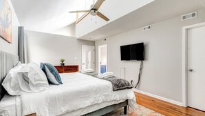 Une chambre moderne équipée d’un lit, d’un ventilateur de plafond, d’une télévision et d’un radiateur.
