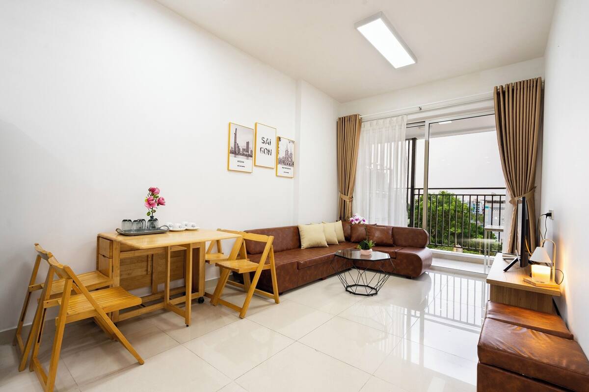 Ein modernes Wohnzimmer mit einer Couch, einem Couchtisch, einem Holzespeisebereich und einem Balkon mit Vorhängen.