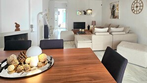 Ein modernes Wohnzimmer mit Esstisch aus Holz, einer Sofagarnitur und einem Flachbildfernseher.