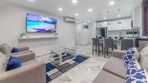 A modern living room with a flat-screen TV, a glass coffee table, and a sofa. - Ala Wishes Luxury Condo (Sosúa)