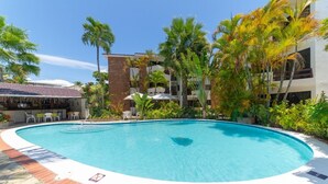 A swimming pool surrounded by palm trees and a building with balconies. - Ala Wishes Luxury Condo (Sosúa)