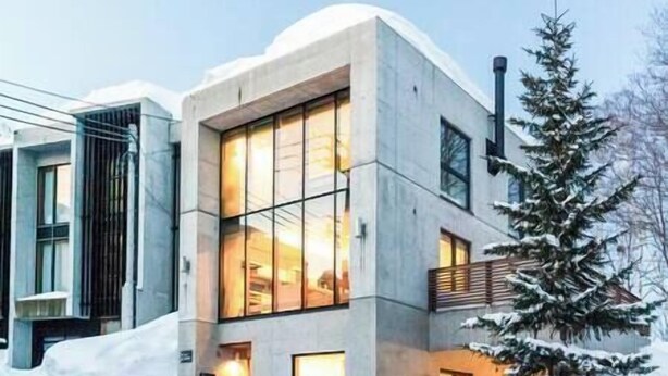 Un edificio moderno con amplios ventanales y suelo cubierto de nieve.