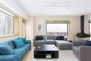 Uma sala de estar moderna com sofá seccional, mesa de centro e lareira.