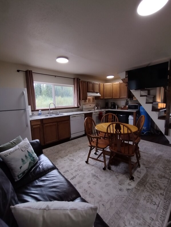 A compact living space with a kitchen, dining area, and a staircase.