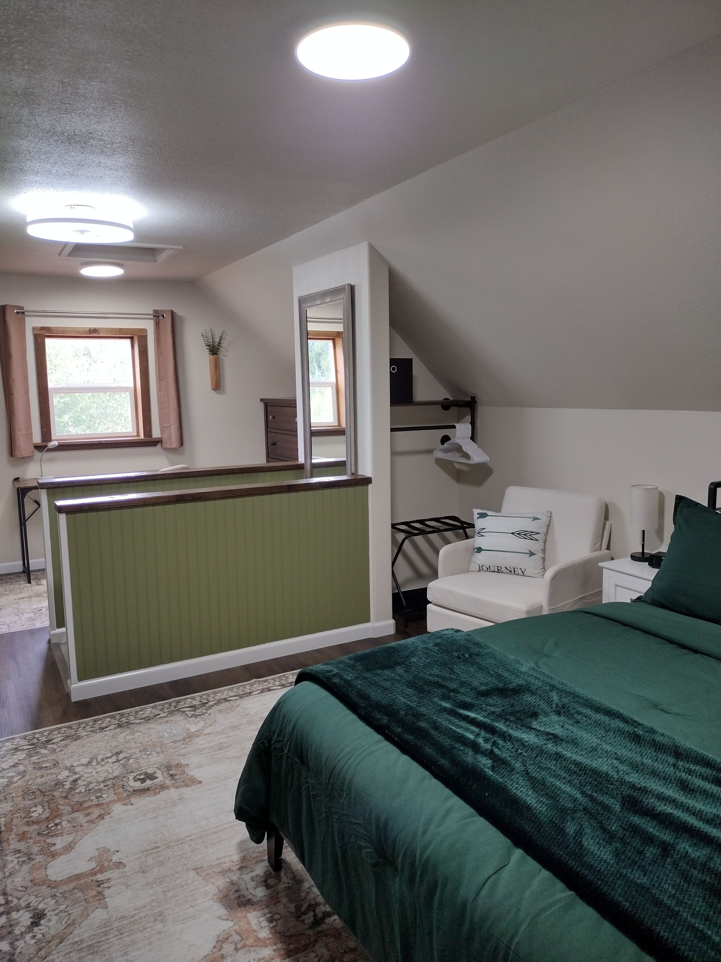 Une chambre à coucher avec un lit, une chaise, un bureau, une fenêtre et un miroir.