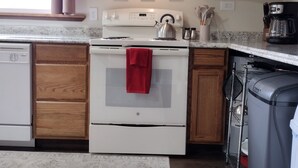 Una cocina con armarios de madera, una estufa blanca y una cafetera.