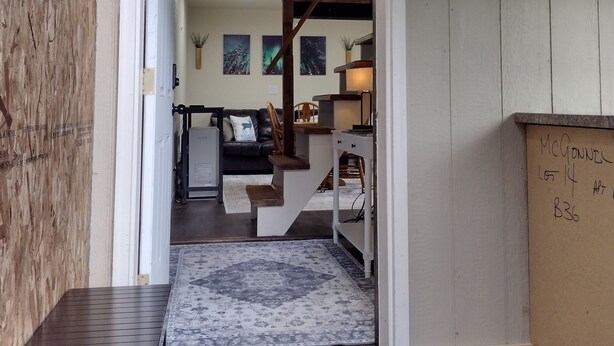 Un interior de madera con una escalera que conduce a una sala de estar, una mesita y un armario.