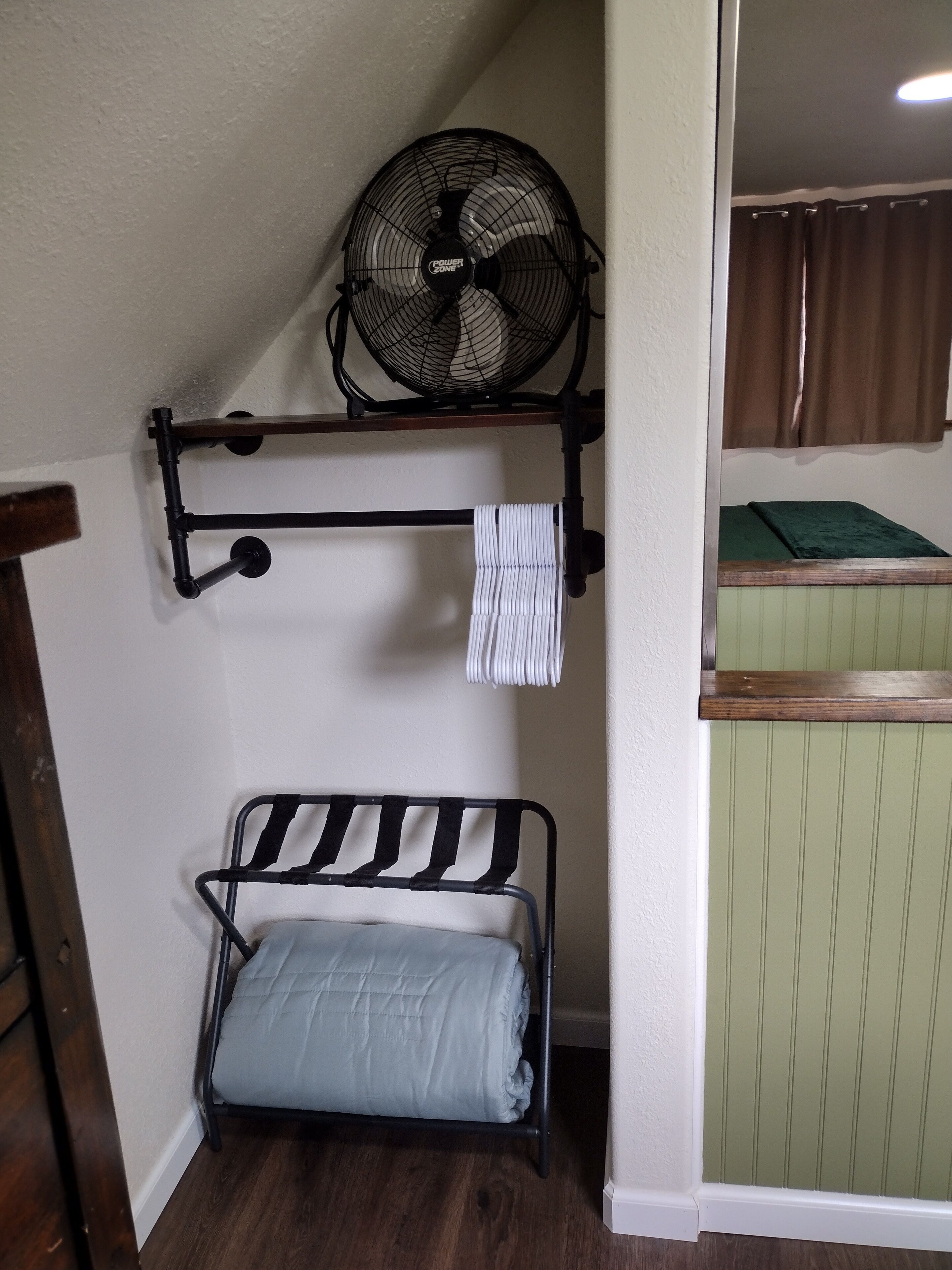 A bunk bed with a fan above and a towel rack below.