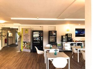 A hotel lobby with a reception desk, seating area, and a television screen. - Hotel K1 (Grammetal)