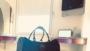 A hotel room with a bed, a desk with a laptop, a television, and a blue bag on the bed. - Hotel K1 (Grammetal)