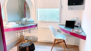 Un bagno moderno con uno specchio grande, un lavandino, un water, una finestra e una scrivania con un portatile.