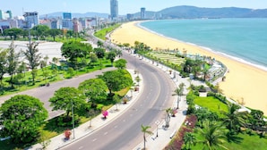 A coastal road with a beach on one side and a cityscape on the other. - FLC Sea Tower Quy Nhon Apartment (Quy Nhon Nam)