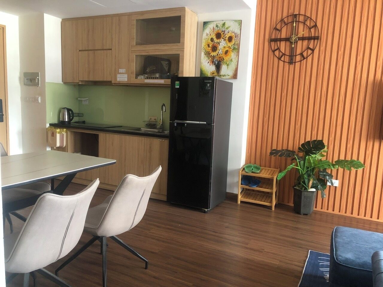 Une cuisine moderne avec des meubles en bois, un réfrigérateur noir et un coin repas comprenant deux chaises.