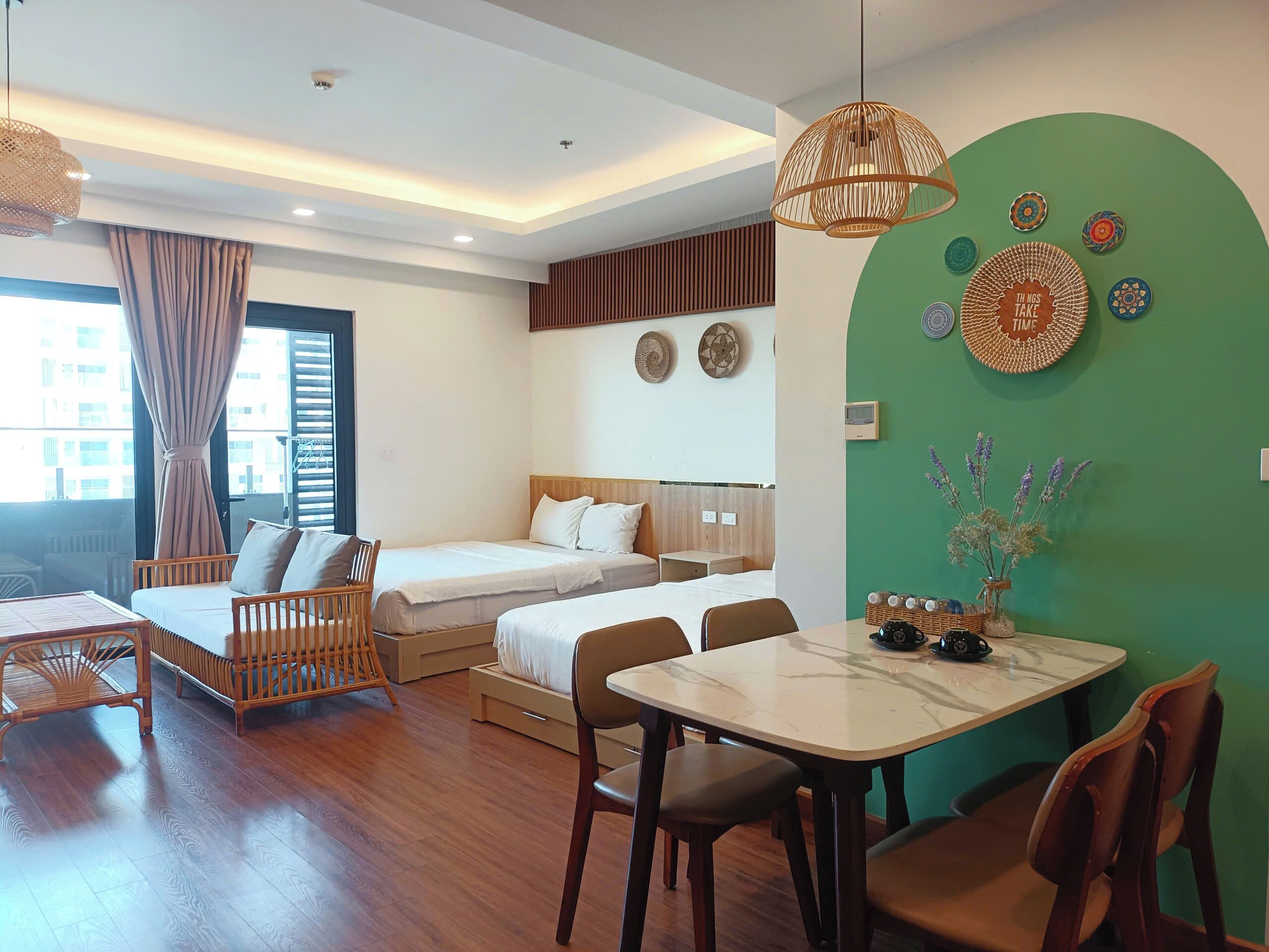 Une chambre d’hôtel avec un lit, un bureau et une table à manger. Il y a des assiettes décoratives accrochées au mur et une horloge.