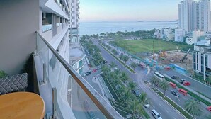 A high-rise building with a balcony overlooking a busy street and a body of water. - FLC Sea Tower Quy Nhon Apartment (Quy Nhon Nam)