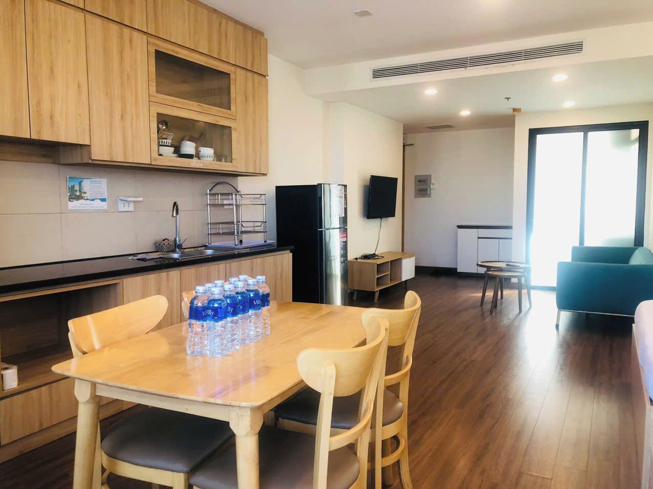 A modern kitchen with wooden cabinets, a dining table with chairs, and a refrigerator.