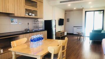 A modern kitchen with wooden cabinets, a dining table with chairs, and a refrigerator.