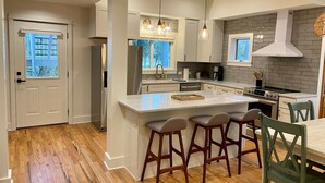 A modern kitchen with a central island, bar stools, and a dining table. - Days Like This -spacious Home Steps From the Beach (Navarre)