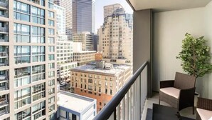 Un balcon offrant une vue sur les immeubles environnants, une plante en pot et des meubles en osier.