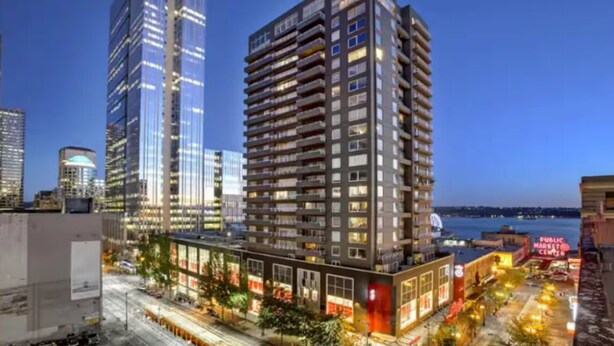 Un immeuble moderne de grande hauteur, doté de nombreux étages, de grandes fenêtres et d’une façade bien éclairée.