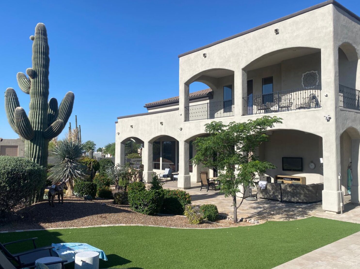 Un bâtiment à deux étages doté d’une cour intérieure comprenant un grand cactus, une statue de cheval et un espace piscine.