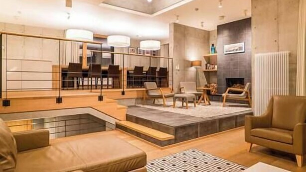 A modern living room with a fireplace, seating area, and a view of the kitchen. - Mizunara Chalet by Elite Havens (Kutchan)