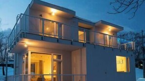 A modern two-story house with a balcony, large windows, and a visible door. - Mizunara Chalet by Elite Havens (Kutchan)