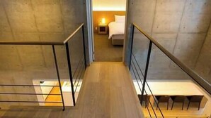 A modern hotel room with a wooden staircase, a bed, and a nightstand with a lamp. - Mizunara Chalet by Elite Havens (Kutchan)
