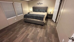 Ett sovrum med en säng, sängbord, en väggmonterad lampa och en dörr.